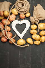Raw potatoes on a black wooden background, space for text