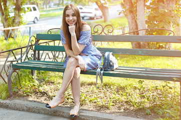 Smiling girl  sitting on bench in summer day