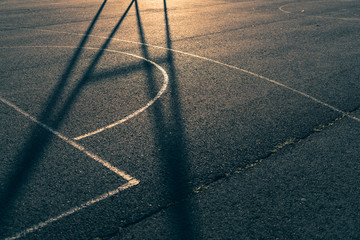 Close-up of a basketball court with golden back light and shadow