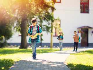 Children with rucksacks standing in the park near school
