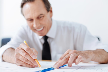 Senior engineer drawing a line with pencil and ruler