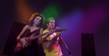 Man singing while a woman plays the guitar 
