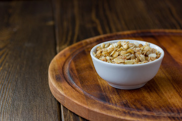 Granola or muesli in white ceramic bowl over wooden table.