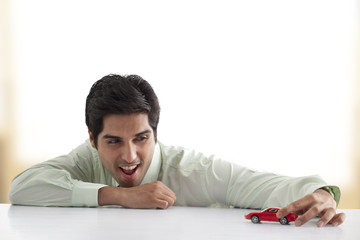 Handsome businessman playing with car model 