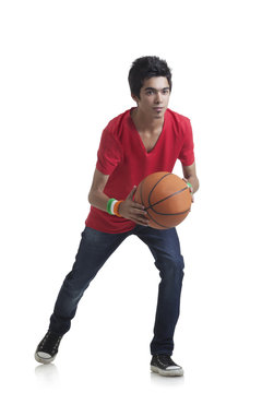 Full length of young boy ready to throw basketball over white background 