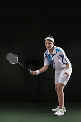 Fototapeta na wymiar Young woman in sportswear playing badminton isolated over black background
