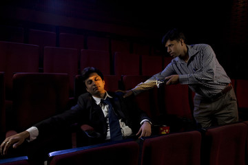 Cinema hall attendant waking a sleeping man 