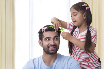 Daughter placing clips in fathers hair and making funny hair style
