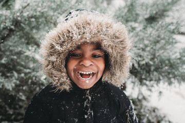 Happy boy standing outdoors in snow during winter