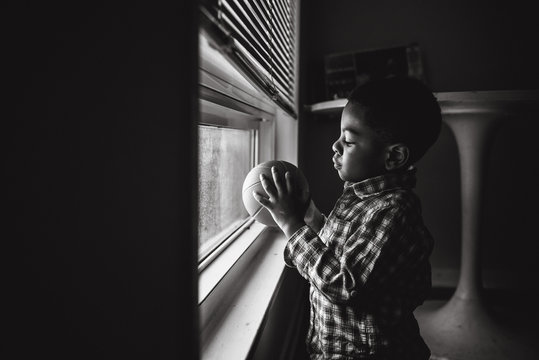 boy holds ball near window