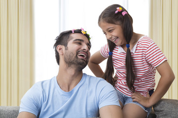 Smiling funny father wearing hair clips like daughter