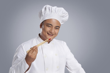 Portrait of chef eating cherry tomato with chopsticks