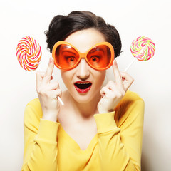 Funny woman wearing big orange glasses holding big lollipop. Bir
