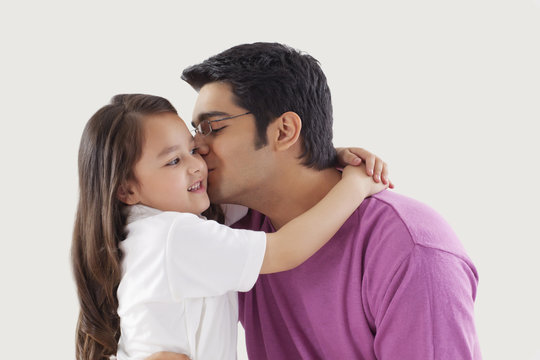 Father kissing daughter on cheeks 