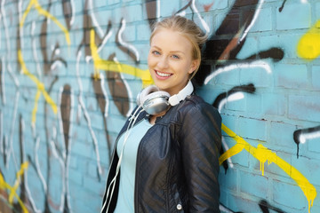 glückliche junge frau lehnt an einer wand mit graffiti in der stadt
