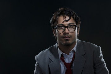 Portrait of confident businessman wearing glasses against black background