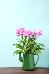 Bouquet of peony flowers in jug on mint background