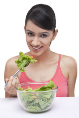 Close-up portrait of smiling young woman with bowl of lettuce 