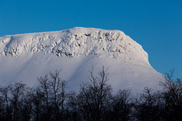 Sunrise light on snow covered mountain with blue sky