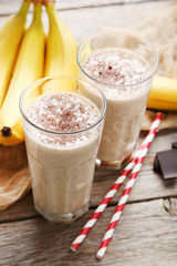Cocktail with bananas in glasses on grey wooden table