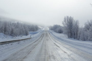 Fototapeta na wymiar Remote frozen road in fog in winter
