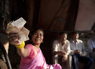 Indian female vendor holding banknotes with customers sitting in background 