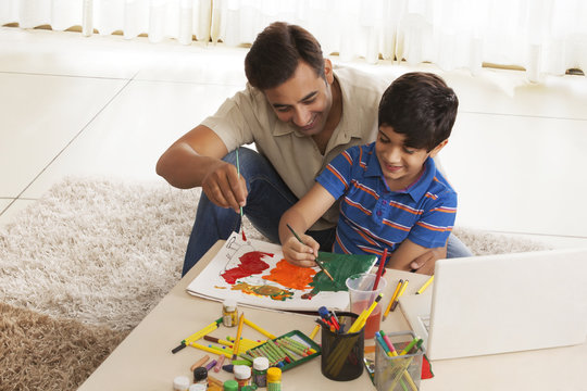 Father and son painting crafts at home