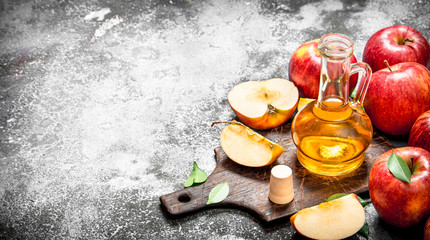 Apple cider vinegar with fresh apples on cutting Board.