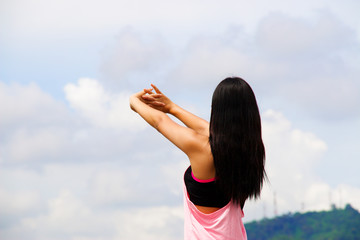 Woman is stretching her arm with blue sky background
