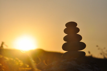 Silhouette of balanced stone pyramid on mountain. Zen rock, concept of balance and harmony