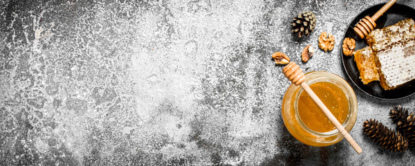 Fresh honey in a jar and honeycomb with nuts.