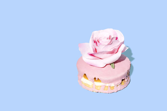 Cake with pink icing and decorative flower against blue background