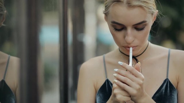 Bad habit. Beautiful woman smokes a cigarette in a city street, slow motion.