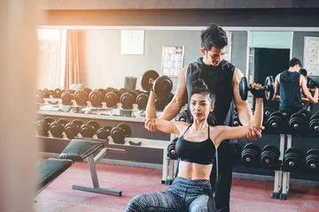  Sport girl doing weight exercises working with heavy dumbbells her personal trainer at Gym workout © joyfotoliakid