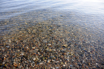 wasseroberfläche über klarem wasser mit blick auf  den kiesuntergrund