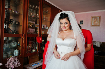 Helpful bridesmaids helping bride to dress up and get ready for her wedding.
