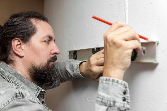 Mann mit Wasserwaage markiert eine Stelle an der Wand