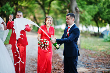 Wedding couple and groomsmen with bridesmaids drinking champagne in the forest.