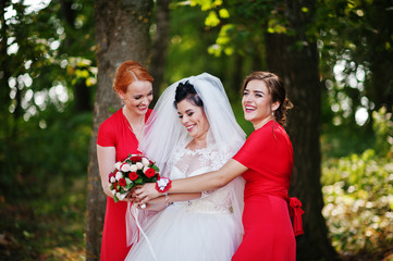 Gentle bride and beautiful bridesmaids are having great fun in the park on a sunny wedding day.