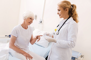 Curious bright elderly woman pointing at pillbox