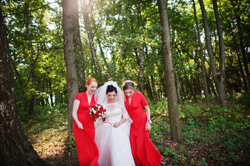 Gentle bride and beautiful bridesmaids are having great fun in the park on a sunny wedding day.