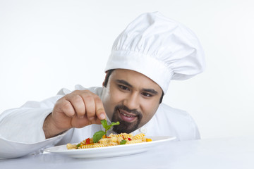 Chef decorating pasta with leaf