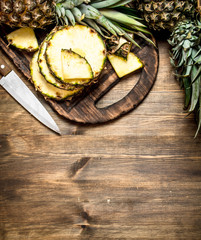 Sliced pineapple on a cutting Board with a knife.
