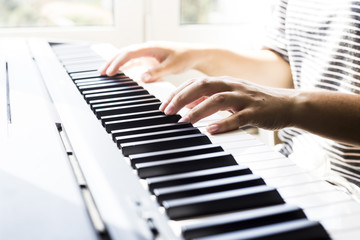 Fototapeta premium A woman playing piano at the window. A cup of coffee is on the instrument