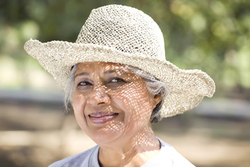 Close-up of smiling mature woman wearing hat at park 