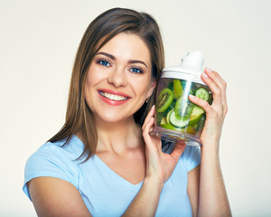 Smiling woman holding green ingredients for smoothie in blender.