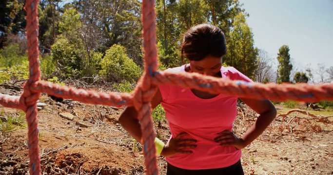 Determined woman climbing a net during obstacle course