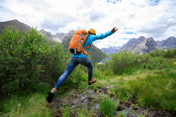 Naklejka na ściany i meble backpacking woman jumping in mountains