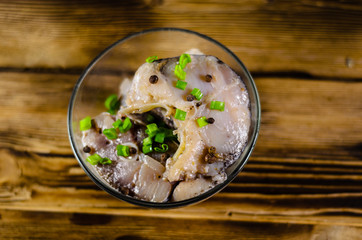 Pieces of the marinated carp in bowl on wooden table. Top view