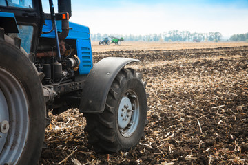 Old blue tractor in a empty field. Agricultural machinery, field work.
